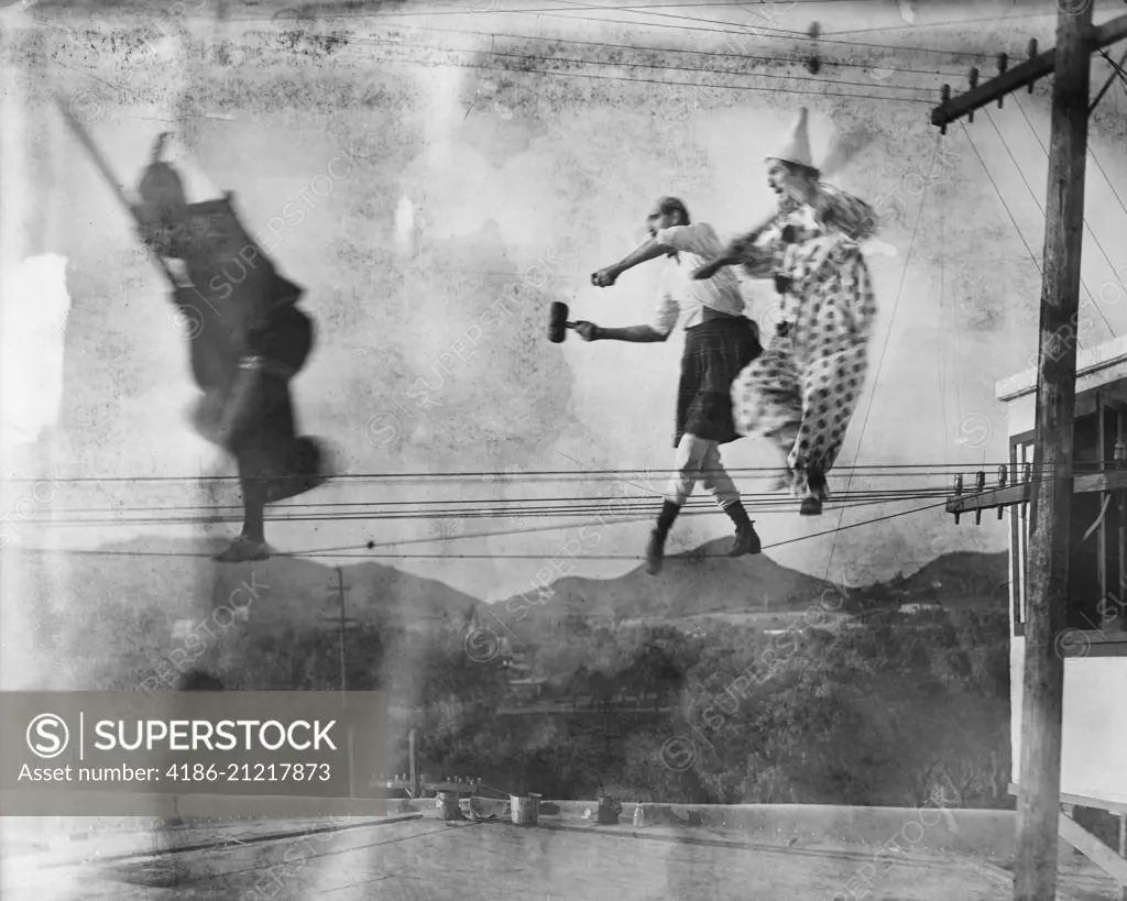 CLOWN AND CIRCUS PERFORMERS WALKING TIGHTROPE ON ELECTRIC UTILITY WIRES SILENT MOVIE STILL DOUBLE EXPOSURE TECHNIQUE