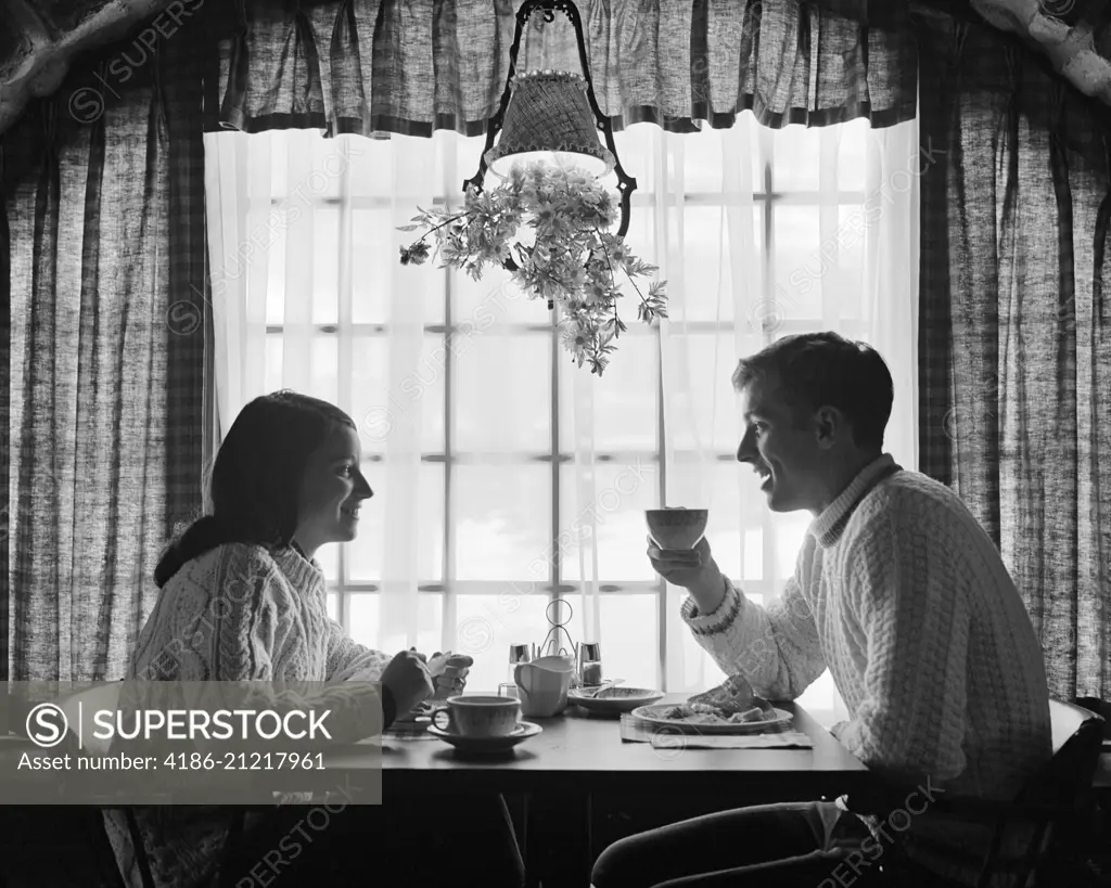 1970s SILHOUETTED COUPLE EATING BREAKFAST AT TABLE BY WINDOW