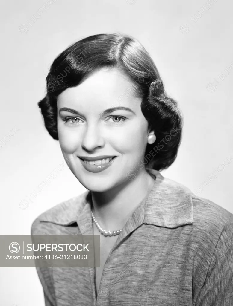 1950s PORTRAIT SMILING BRUNETTE WOMAN WITH PAGE BOY HAIRSTYLE WEARING STRING PEARLS LOOKING AT CAMERA