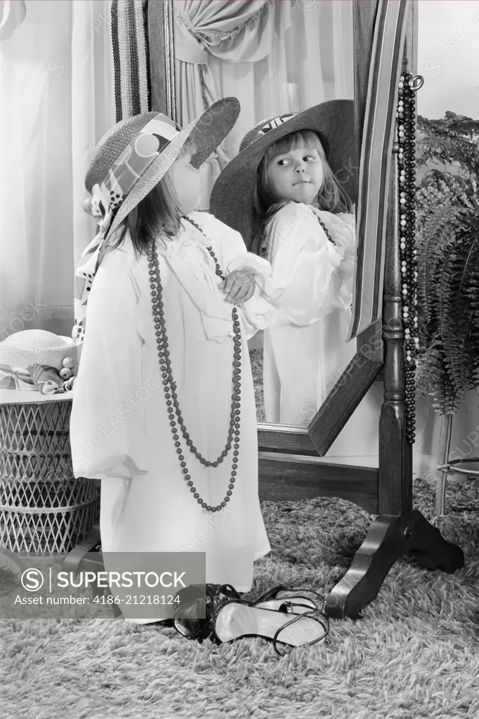 1980s LITTLE GIRL DRESSED UP IN ADULT CLOTHES POSING BEFORE MIRROR FUN PLAY ROLE PLAYING HAT BEAD NECKLACE 