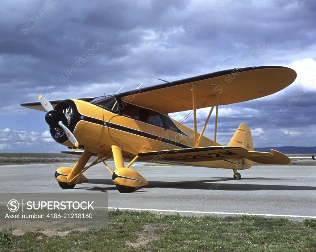 AIRPLANE YELLOW AND BLACK BI-PLANE  ON AIRPORT TARMAC