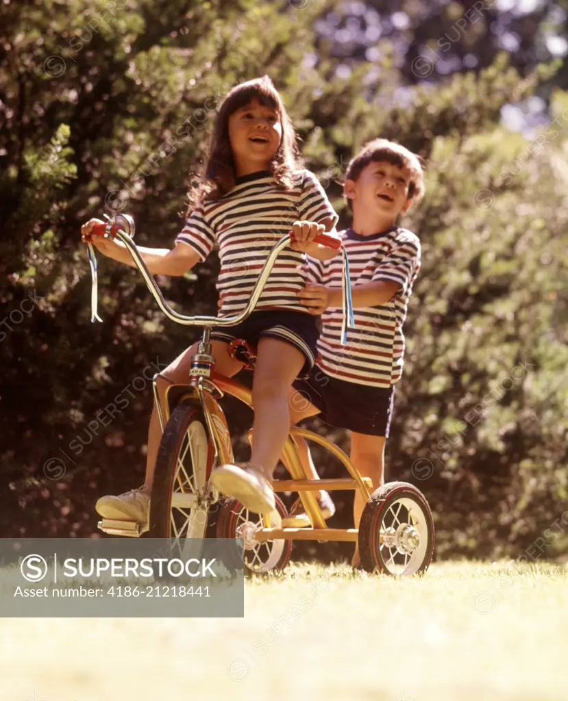 1970s 2 KIDS STRIPED TEE SHIRTS SHORTS RIDING YELLOW TRICYCLE BIKE GIRL STEERING BOY STANDING BACK BIKE