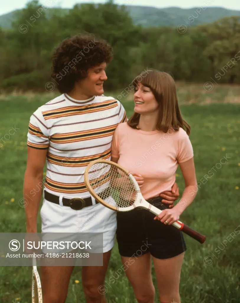 1970s 1980s COUPLE WEARING TENNIS SHORTS HOLDING RACKETS SuperStock