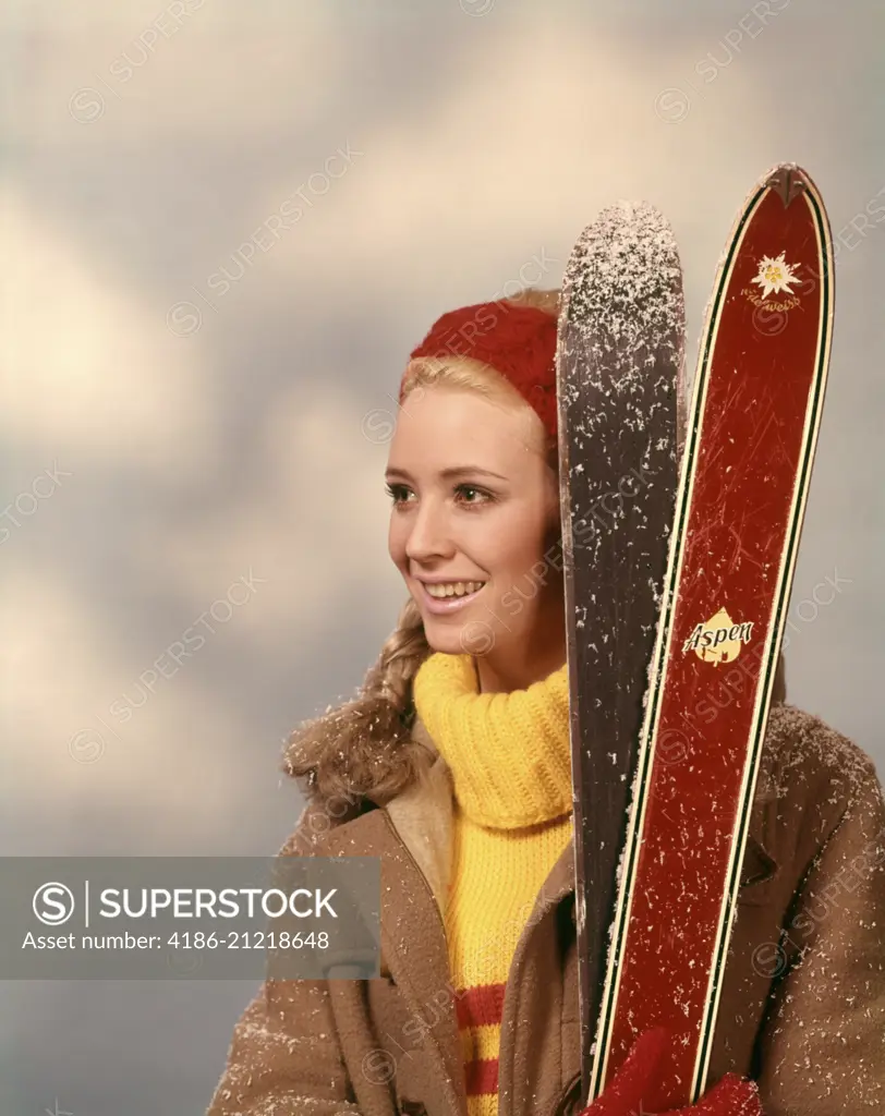 1960s 1970s PORTRAIT WOMAN RED HEADBAND YELLOW TURTLENECK SWEATER HOLDING PAIR OF SKIS SKIER