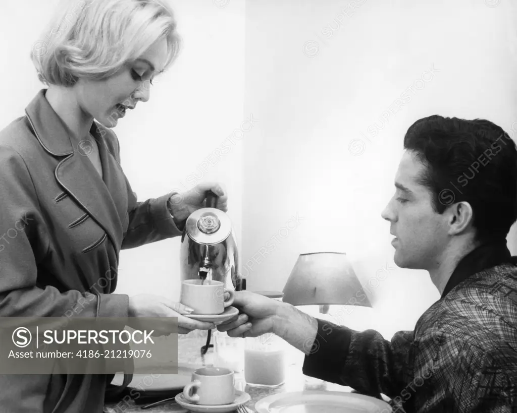 1960s YOUNG COUPLE WEARING ROBES  HAVING MORNING COFFEE FROM ELECTRIC PERCOLATOR COFFEE POT