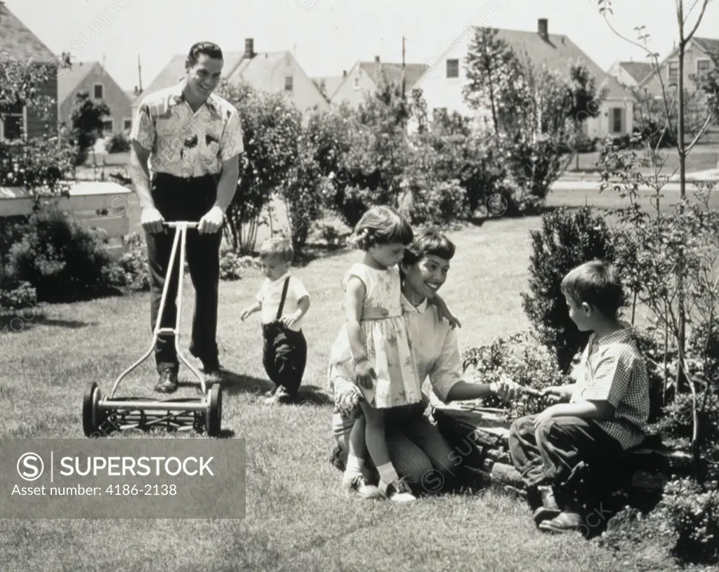 1950S Family In Backyard Dad And Toddler Cutting Grass Mom And Kids Gardening