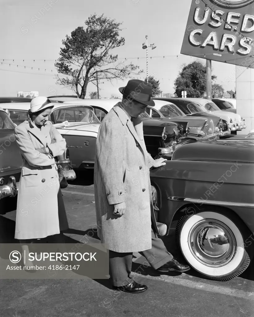 1950S Couple In Used Car Lot Man Kicking Tire