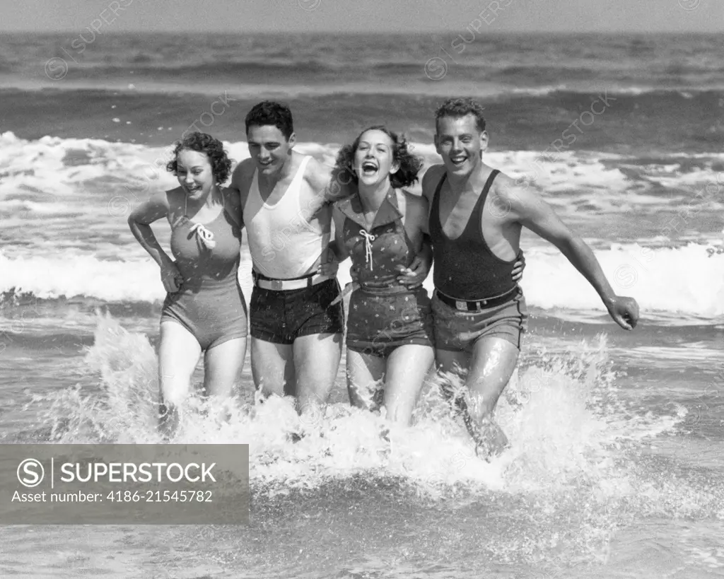 1930s TWO COUPLES MEN WOMEN LAUGHING RUNNING IN OCEAN SURF WAVES