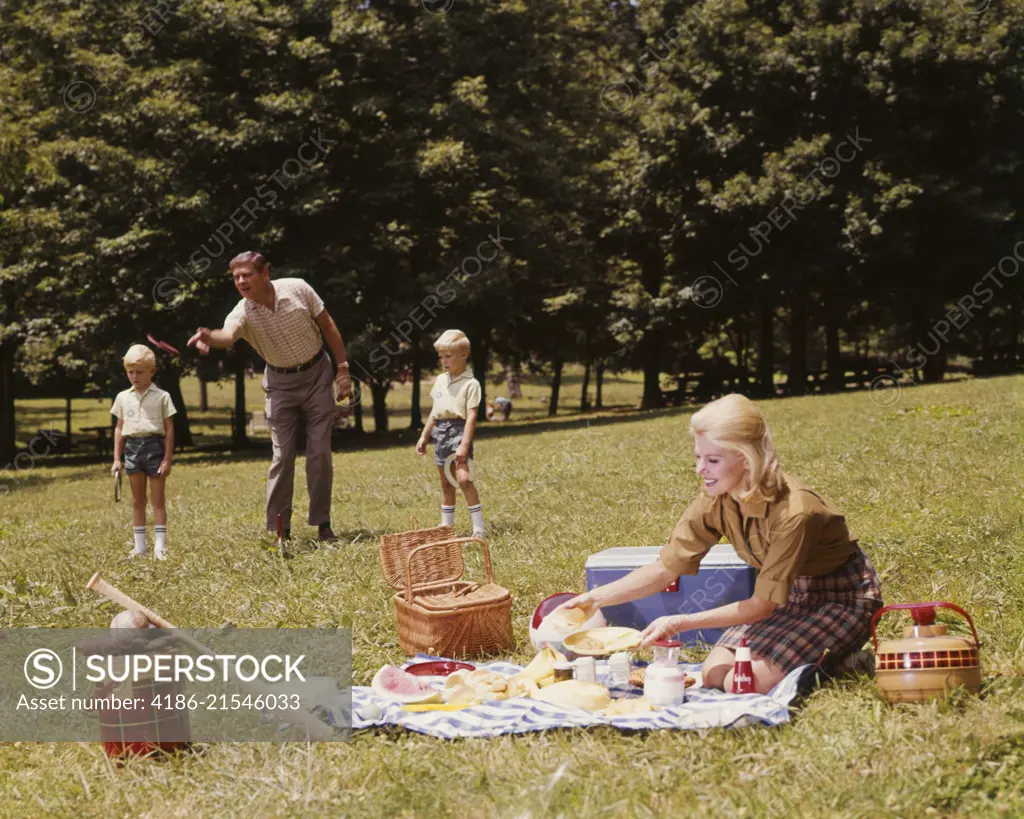 1970s FAMILY PICNIC PLAYING GAME HORSESHOES MOTHER FATHER TWO BOYS  SUMMERTIME - SuperStock