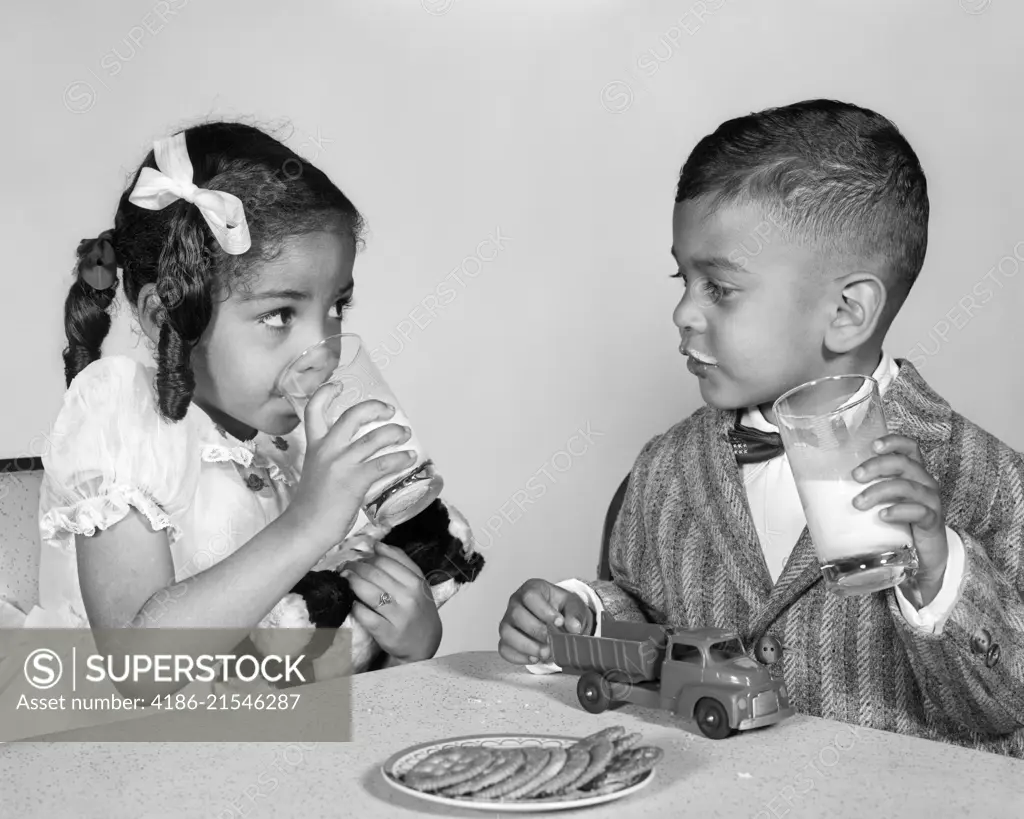 1960s AFRICAN AMERICAN GIRL BOY DRINKING MILK EATING COOKIES