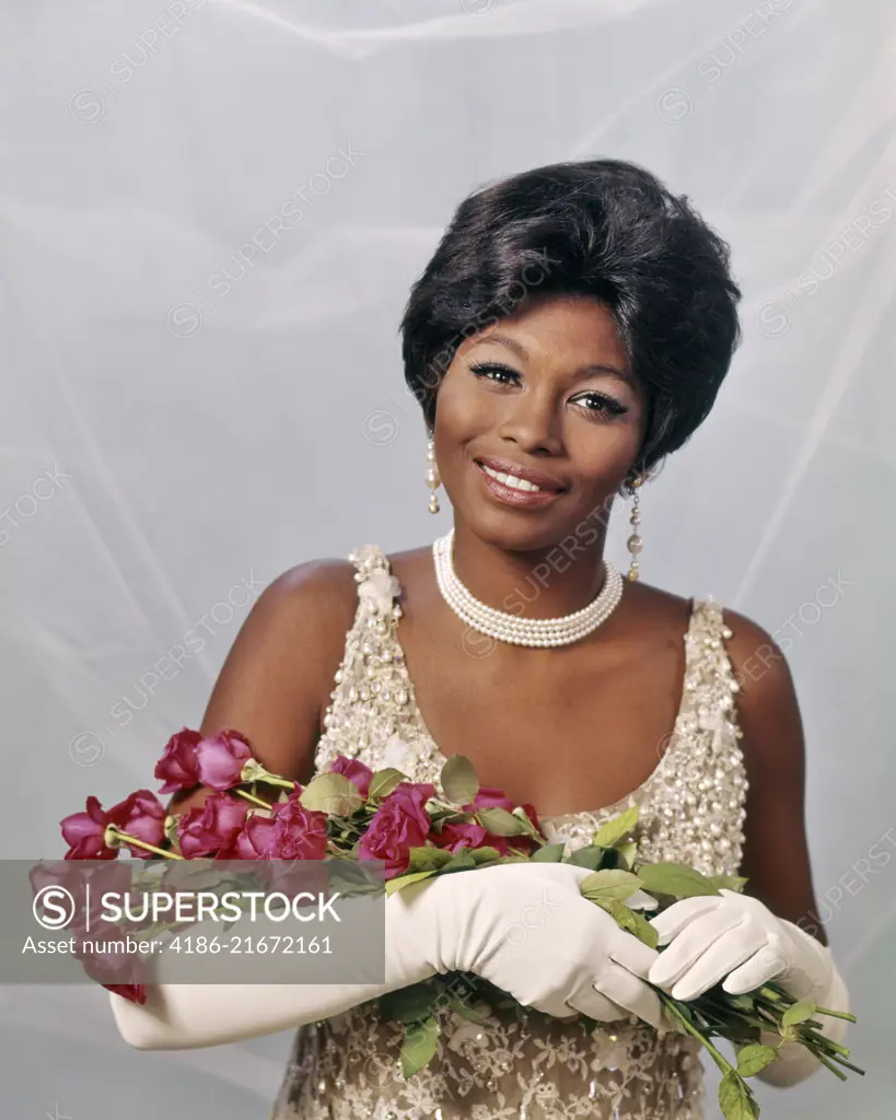 1960s AFRICAN-AMERICAN WOMAN IN PEARL BEADED DRESS WITH LONG WHITE GLOVES AND RED ROSES AWARD BEAUTY QUEEN