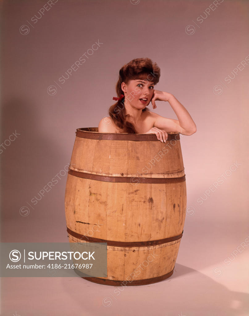 1960s YOUNG NUDE BRUNETTE WOMAN SITTING CROUCHING IN LARGE WOODEN BARREL  LOOKING AT CAMERA - SuperStock