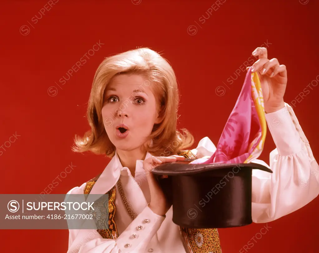 1960s 1970s WOMAN MAGICIAN LOOKING AT CAMERA PULLING SCARF OUT OF TOP HAT