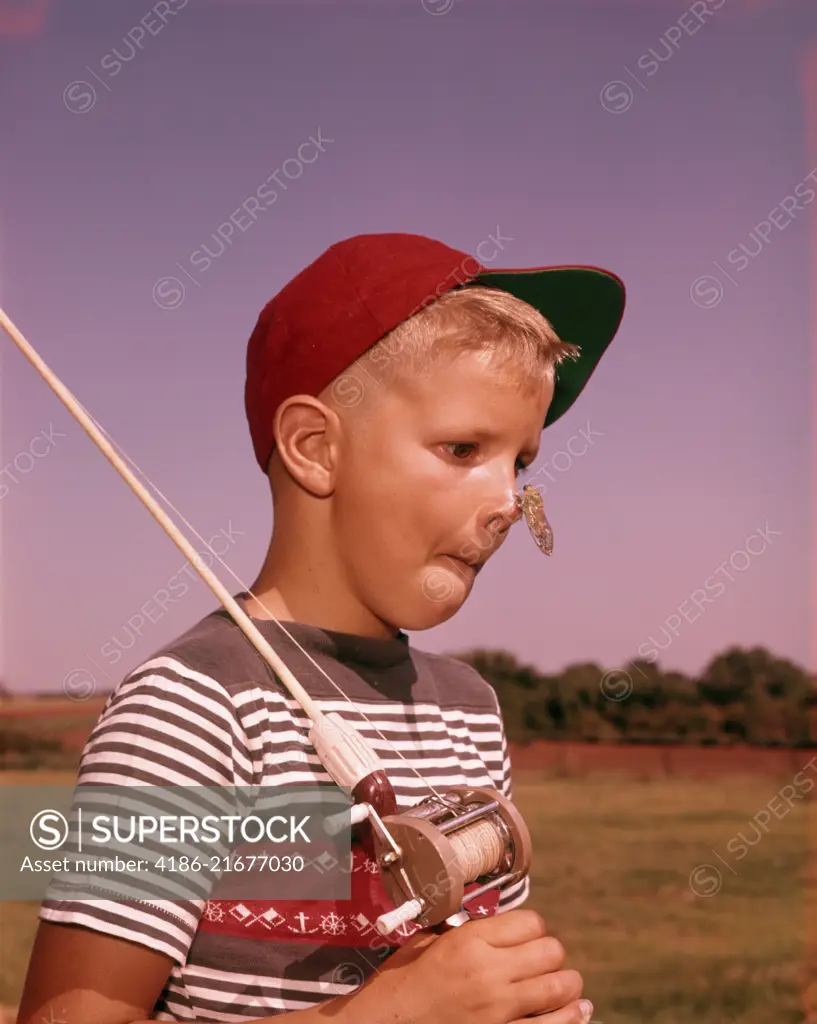 1950s SURPRISED BOY WITH CICADA INSECT ON HIS NOSE HOLDING FISHING POLE WEARING RED BALL CAP