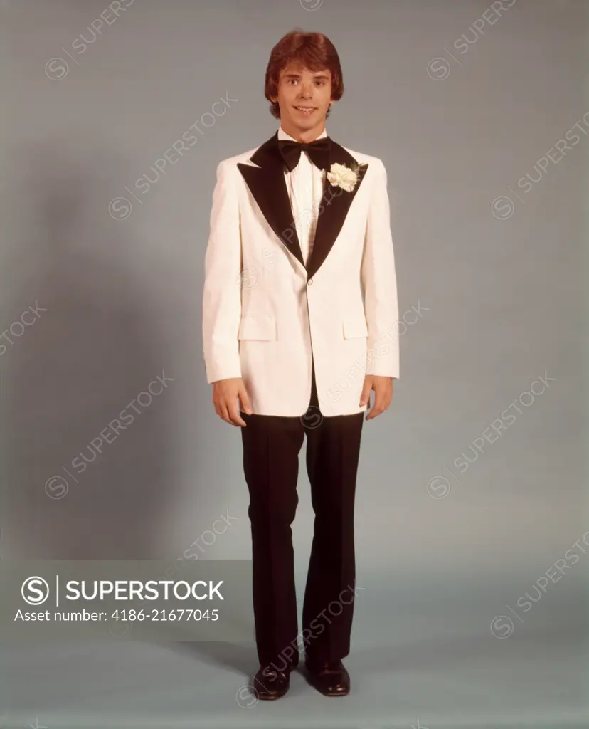 1970s TEEN BOY FULL FIGURE PORTRAIT WEARING FORMAL TUXEDO WHITE JACKET FOR PROM DATE STANDING LOOKING AT CAMERA