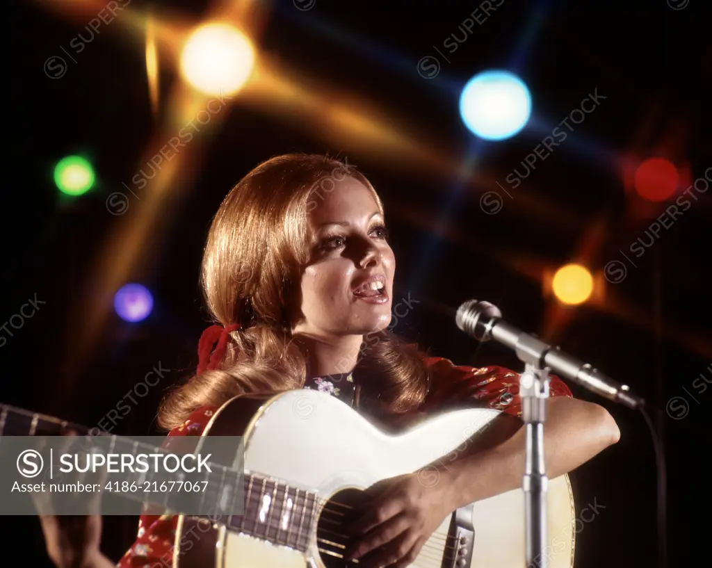 1970s WOMAN PLAYING GUITAR SINGING INTO MICROPHONE COLORED SPOTLIGHTS