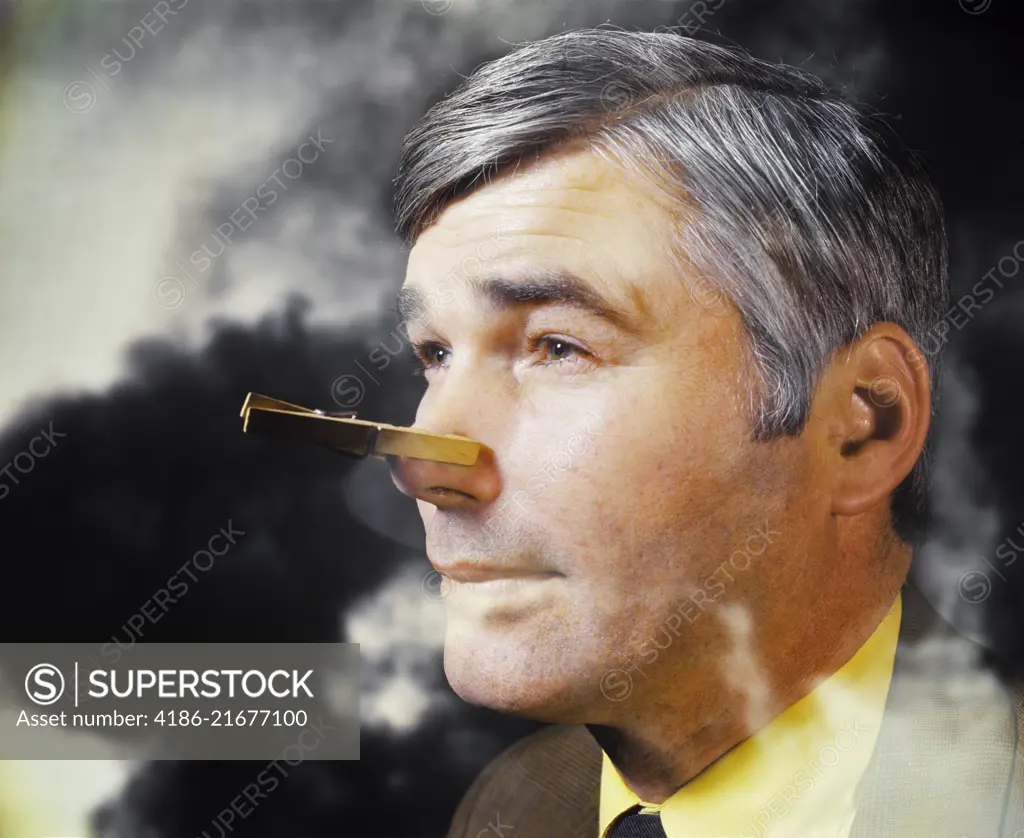 1970s MAN IN SMOKE BAD ATMOSPHERE WITH CLOTHESPIN ON HIS NOSE BECAUSE OF SMELL ODOR POLLUTION 