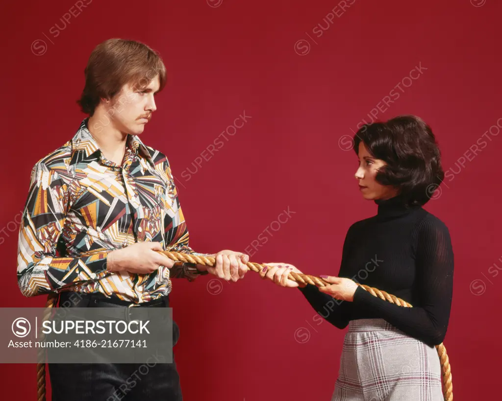 1970s ANGRY COUPLE AT OPPOSITE ENDS OF A ROPE TUG OF WAR 