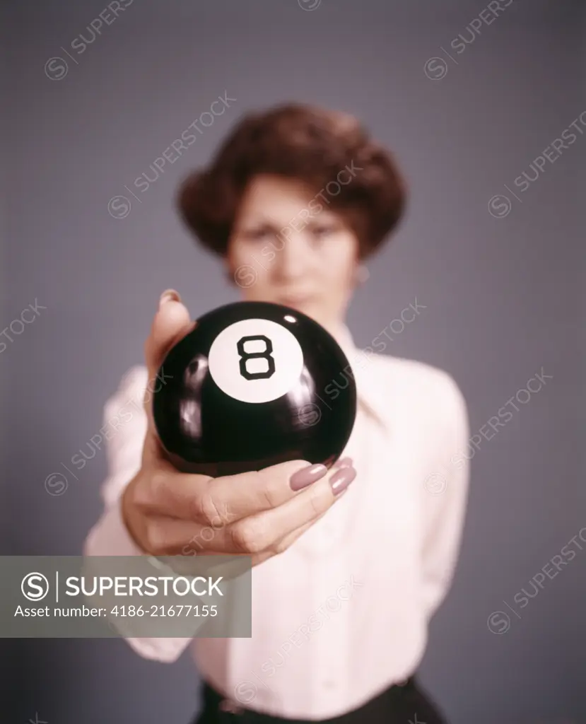 1970s WOMAN STANDING BEHIND HOLDING AN EIGHT BALL LOOKING AT CAMERA