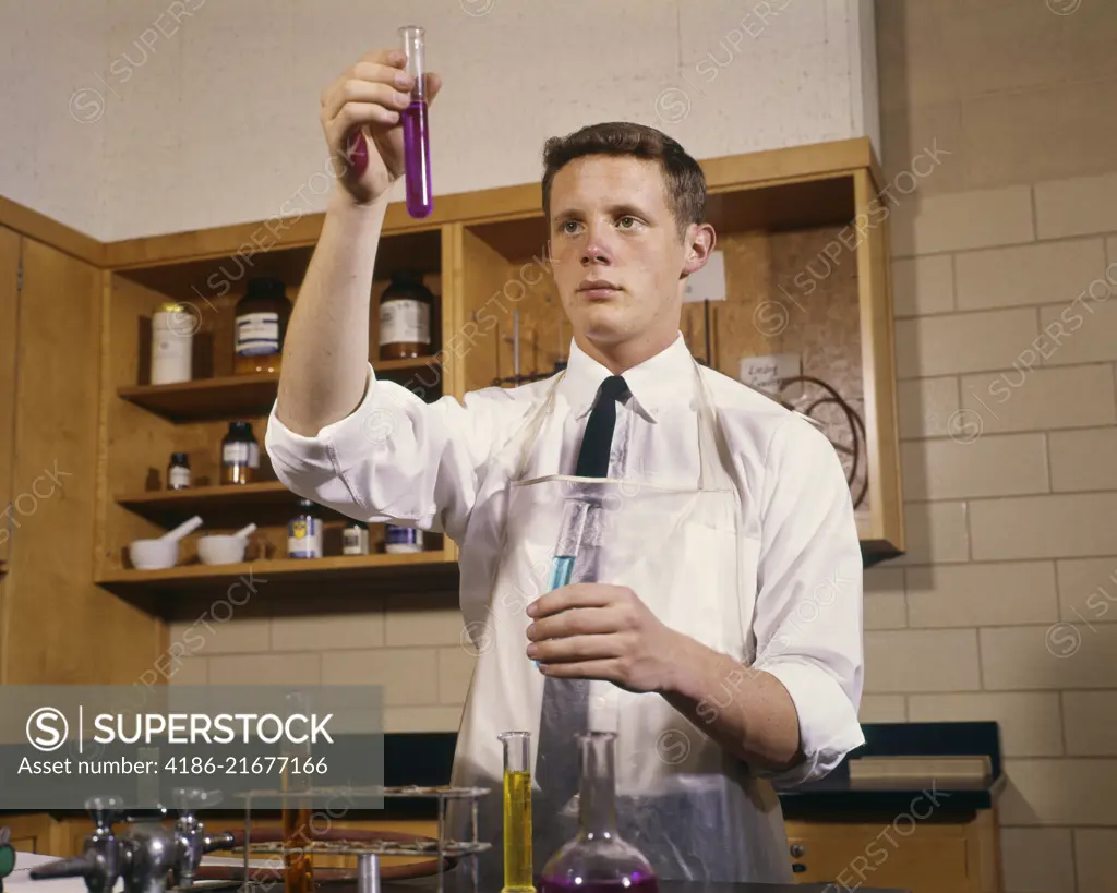 1960s MALE HIGH SCHOOL TEENAGE STUDENT IN CHEMISTRY LABORATORY HOLDING TEST TUBES