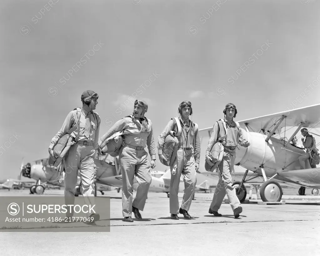 1940S FOUR U.S. NAVY PILOTS WALKING TOGETHER ON TARMAC RETURNING FROM AIR MANEUVERS AT THE PHILADELPHIA NAVY YARD PA USA