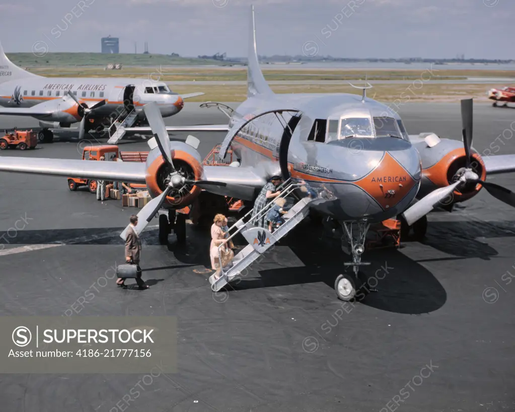 1950s TWO AMERICAN AIRLINE PROPELLER AIRPLANES ON TARMAC WITH PASSENGERS CLIMBING ABOARD LAGUARDIA AIRPORT NEW YORK USA