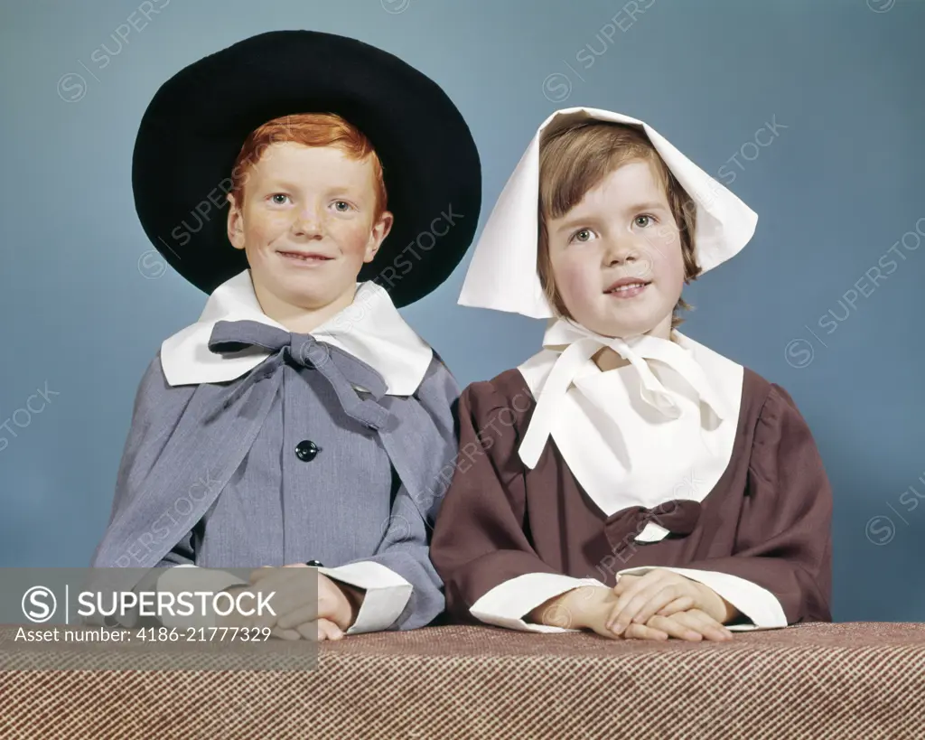 1950s 1960s BOY GIRL IN PILGRIM COSTUMES FOR ELEMENTARY SCHOOL THANKSGIVING PLAY LOOKING AT CAMERA