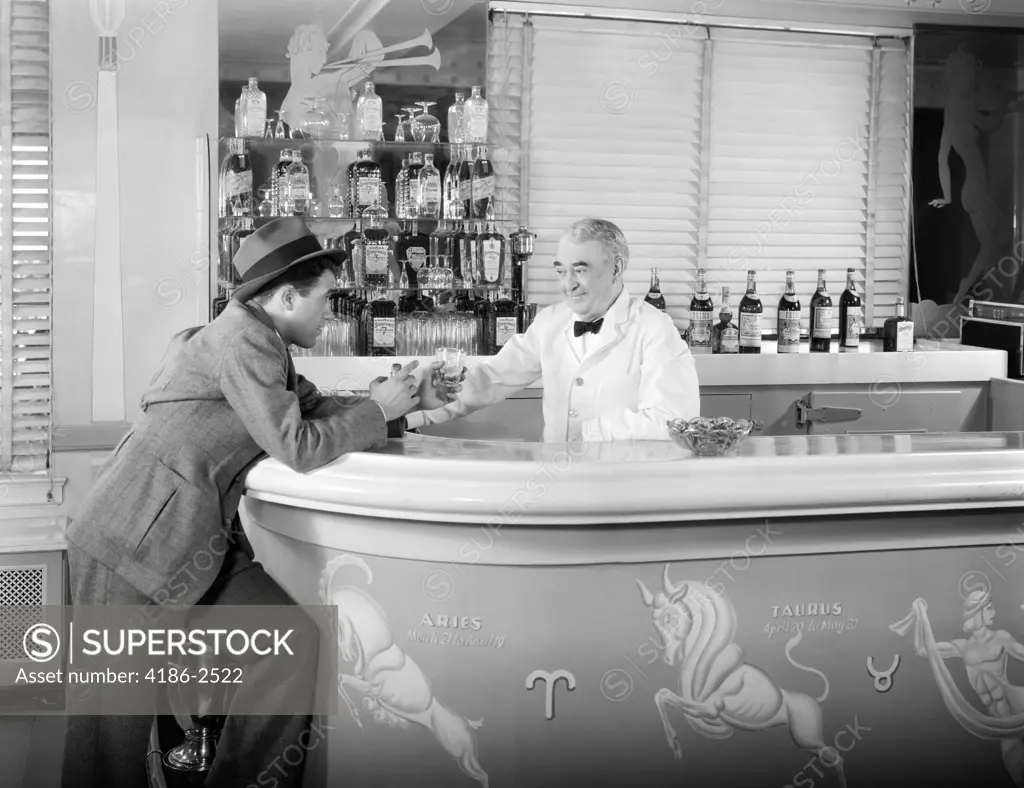 1930S 1940S 1950S Man Leaning On Bar Ordering Another Alcoholic Drink From Bartender In Art Deco Style Cocktail Lounge