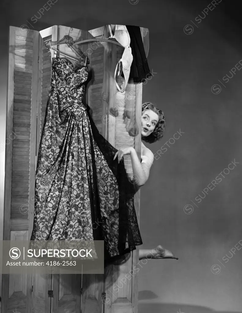 1950S Woman Peeking From Behind Screen At Evening Gown Getting Dressed