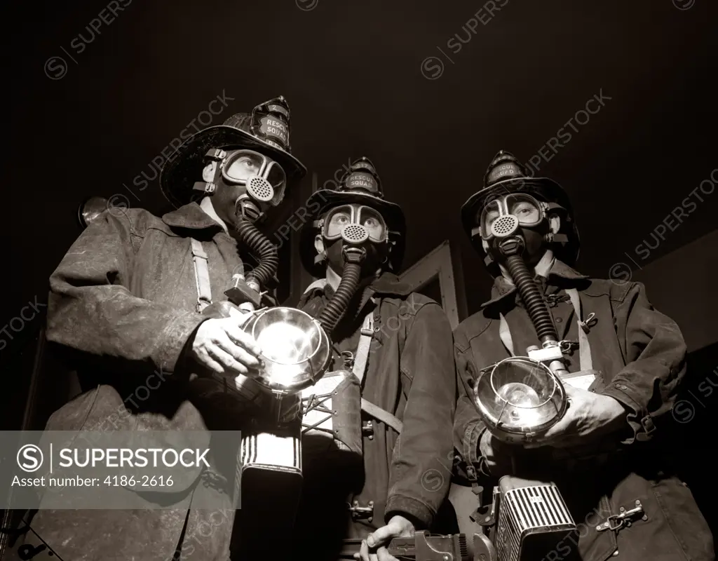 1950S Trio Of Rescue Squad Firemen Wearing Respirator Masks Carrying Flashlights And Fire Equipment