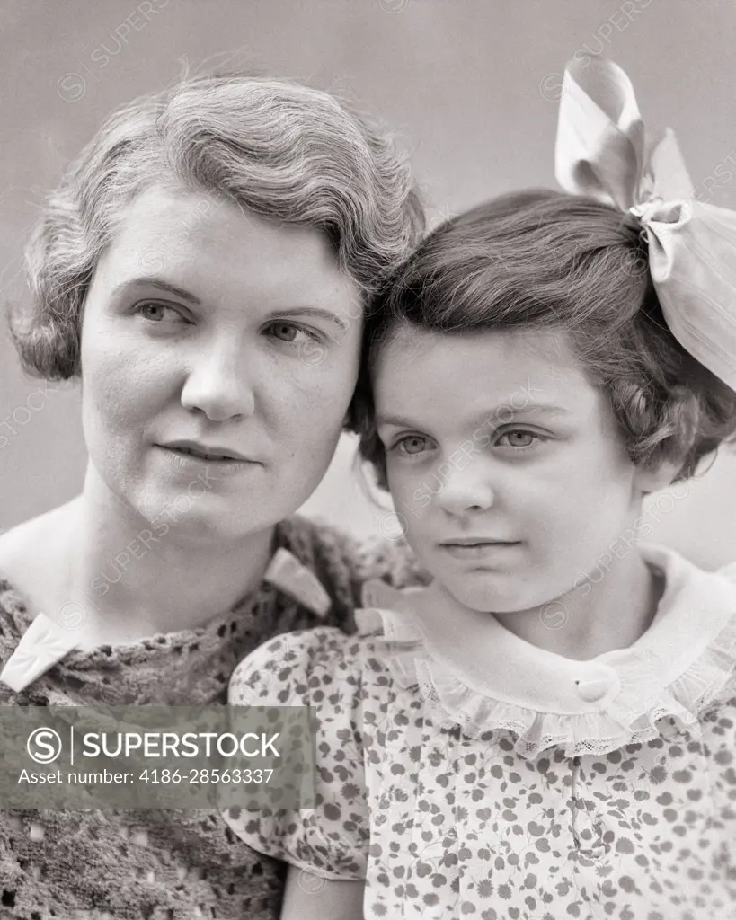 1930s PORTRAIT OF OLDER MATURE WOMAN MOTHER AND YOUNG GIRL DAUGHTER BOTH  WITH SERIOUS FACIAL EXPRESSIONS - SuperStock