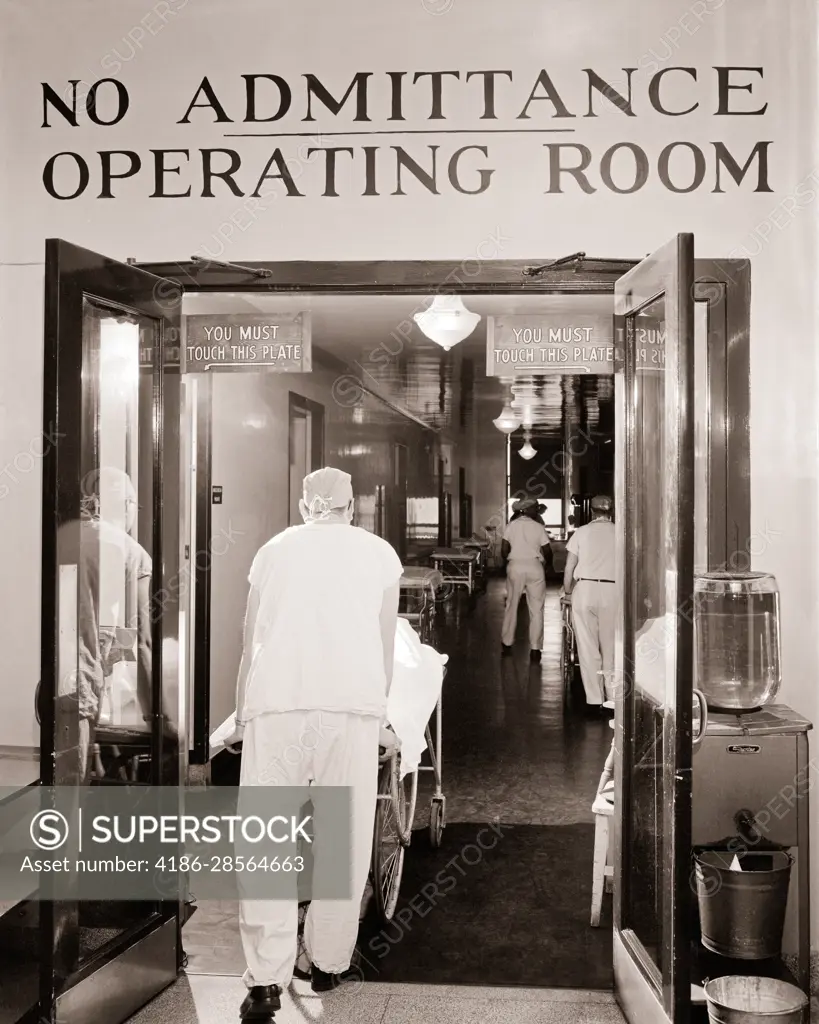 1950s BACK VIEW OF ORDERLY WEARING SCRUBS PUSHING GURNEY WITH PATIENT INTO  THE OPERATING ROOM CORRIDOR SIGN SAYS NO ADMITTANCE - SuperStock