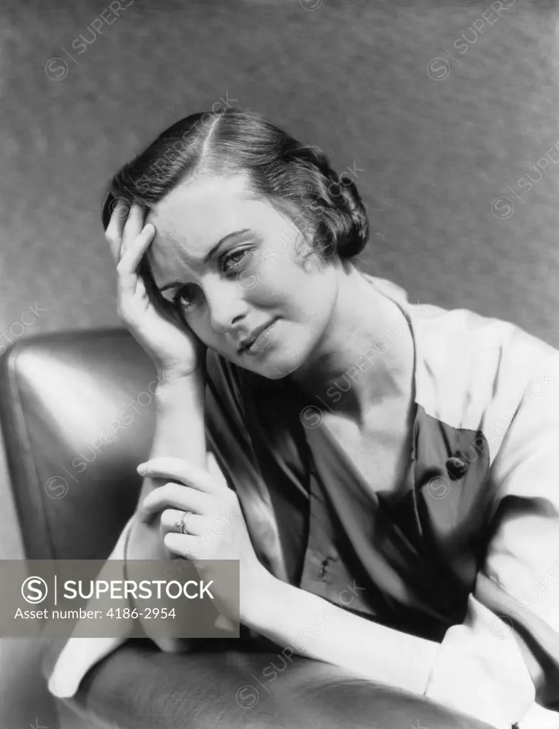 1930S 1940S Woman Sitting In Chair Worried Sad Expression One Hand Up To Her Forehead  