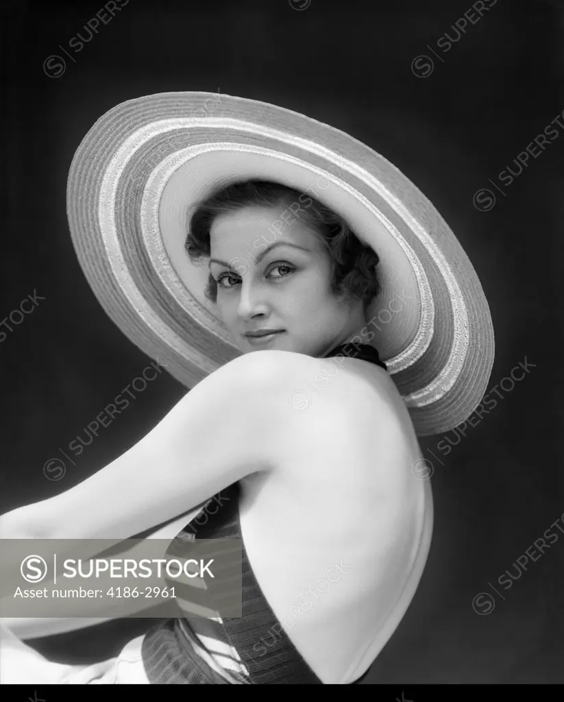 1930S Woman Wearing A Striped Halter Top & Wide Brim Striped Straw Hat Looking Over Shoulder