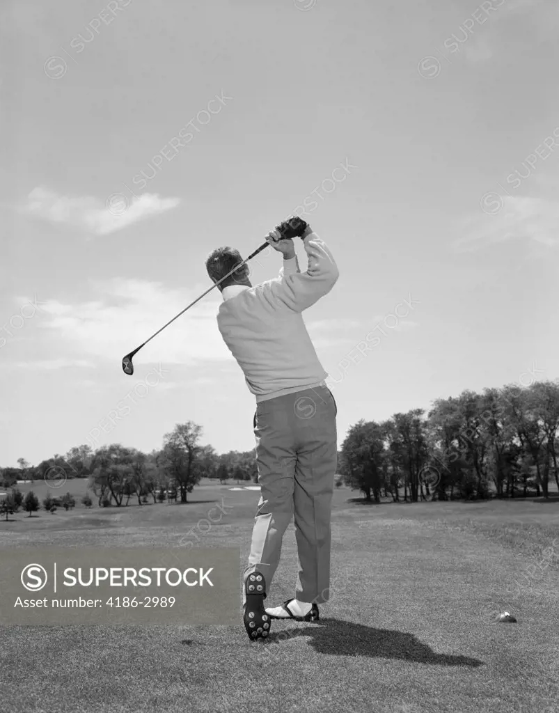 1950S 1960S Rear View Man Swinging Golf Club - SuperStock
