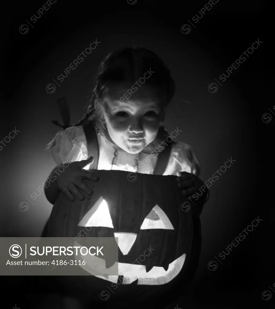 1950S Little Girl Standing Over Carved Pumpkin Face Lit By Candle