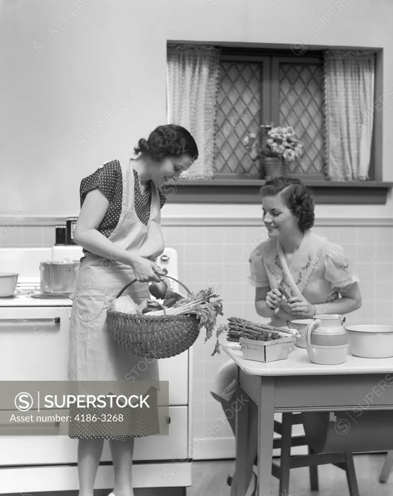 1930S 1940S Two Women At Kitchen Table With A Basket Of Vegetables Asparagus Stove