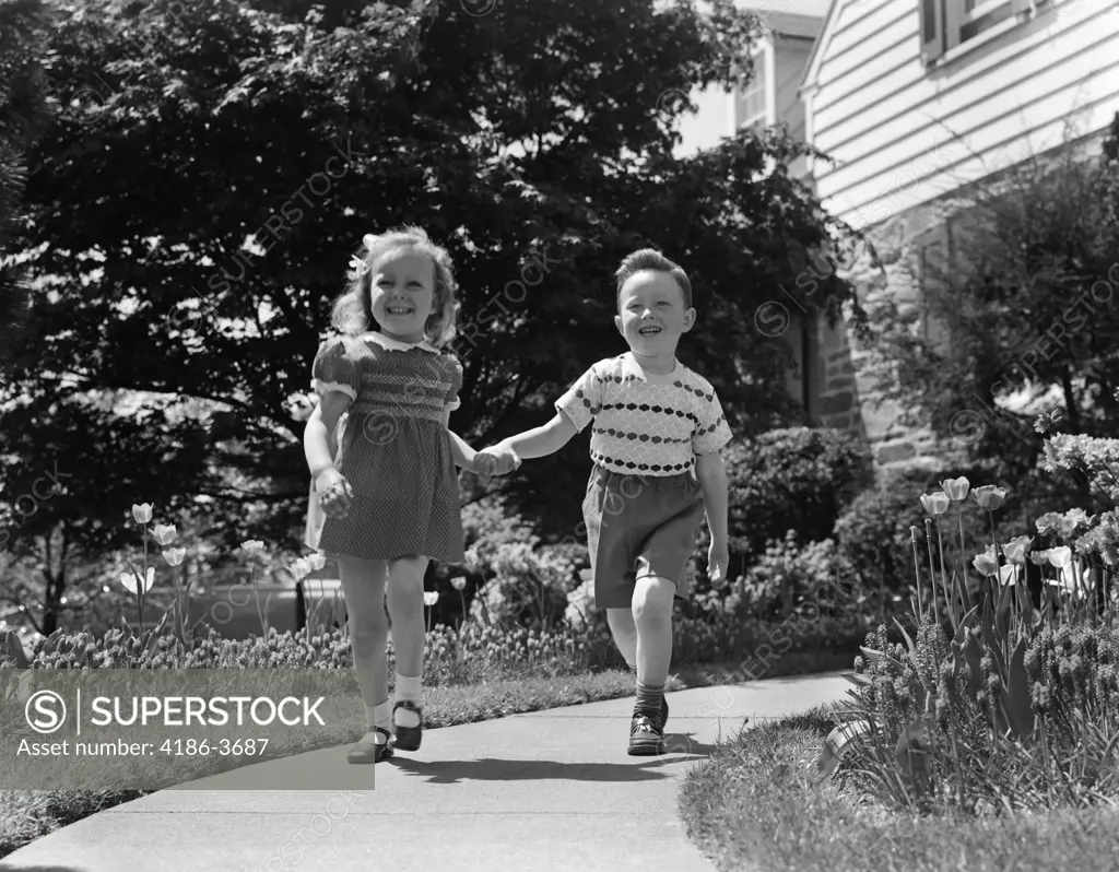 1950S Two Children Holding Hands Smiling Walking Along Sidewalk