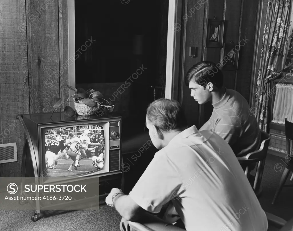 1960S 1970S Teen Boy Watching Football Game On Television With Adult Dad