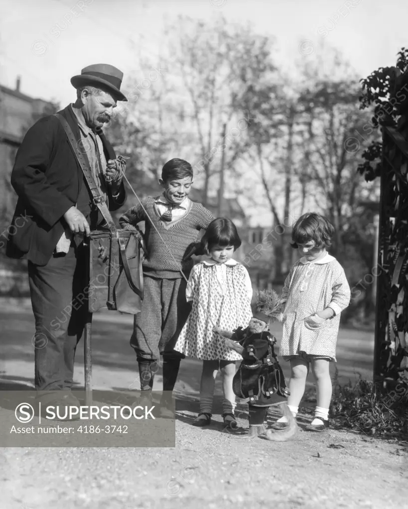 1920S Group Of Three Children Watching Organ Grinder'S Monkey In Costume Standing On Hind Legs