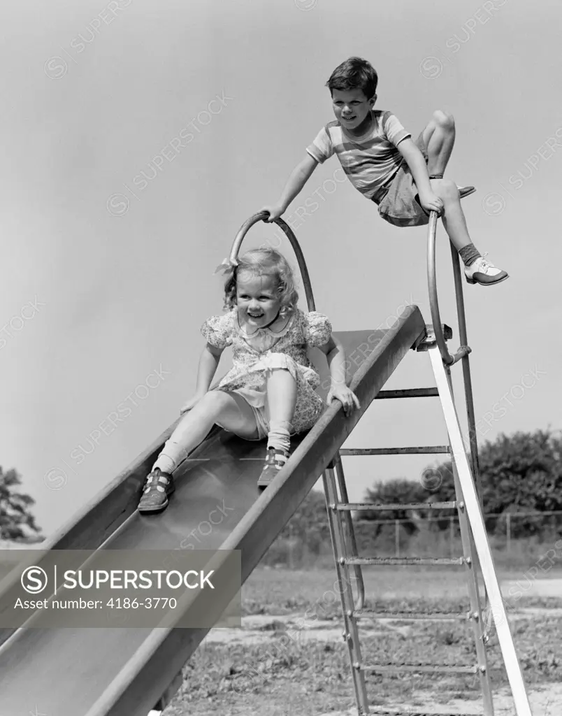 1930S Girl Going Down Slide Boy Waiting At Top To Go Down Summer Outdoor -  SuperStock