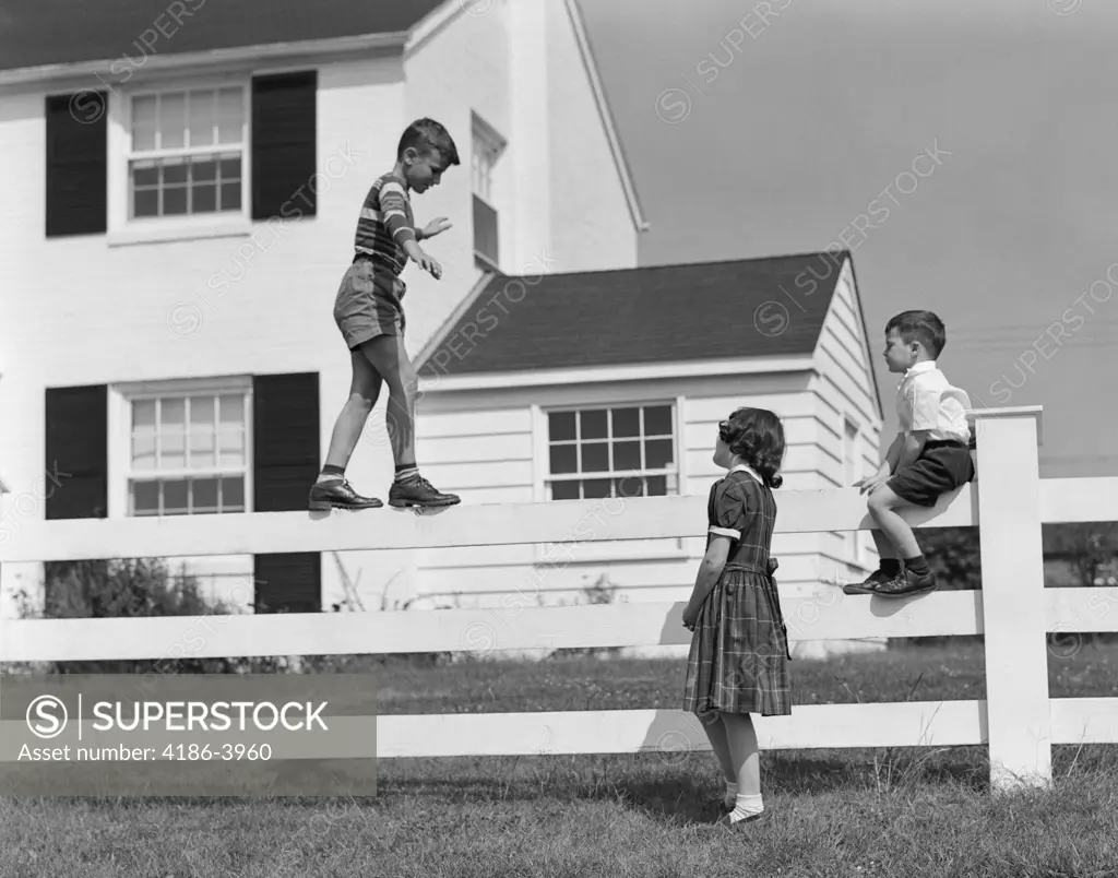 1950S Boy Walking Balancing On Fence Other Children Standing Sitting Next To Fence  