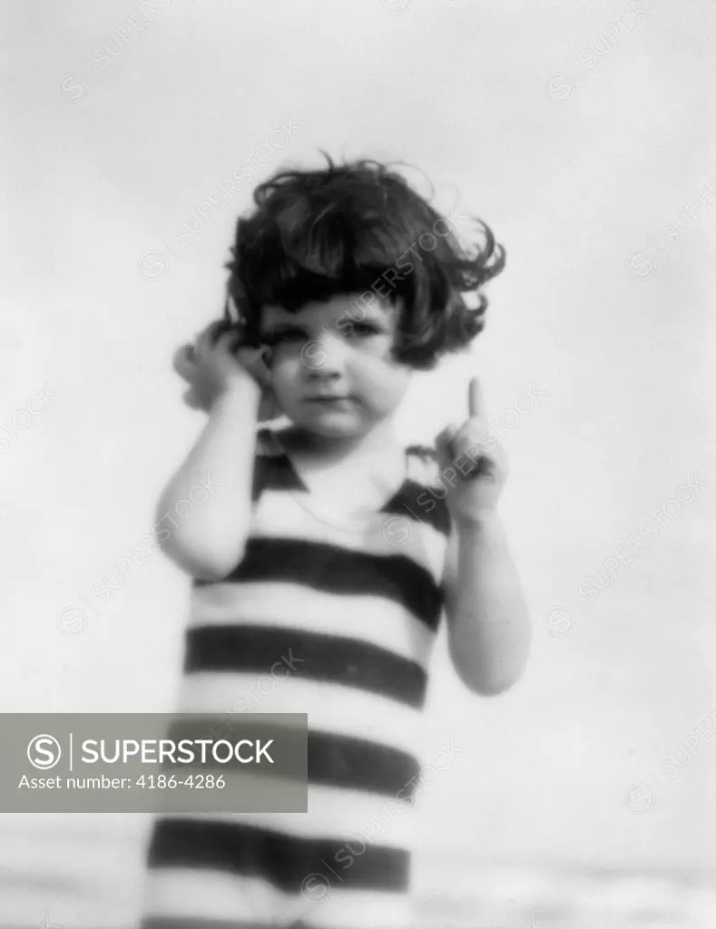 1920S Girl In Striped Bathing Suit Holding Seashell Up To Ear