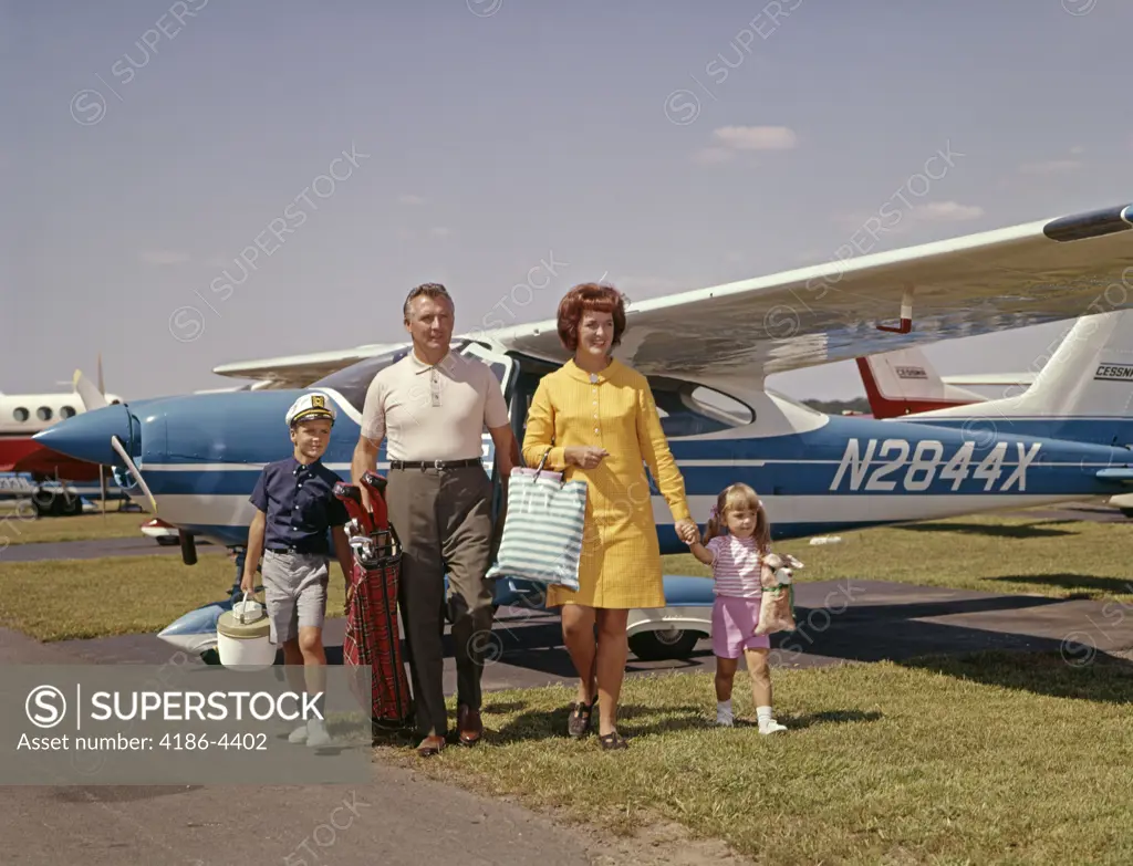 1960S Family Of 4 Walking From Private Plane Across Tarmac Travel Trip Luggage Mother Father Son Daughter