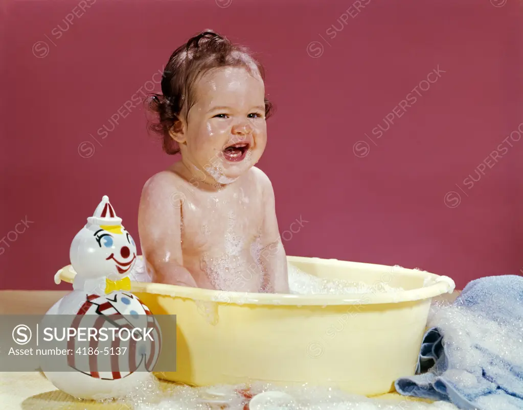 1960S Crying Brunette Baby Sitting In Yellow Plastic Bath Tub With Toy Clown