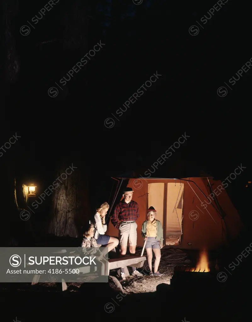 1960S Night Scene Family Gazing Into Campfire By Tent  