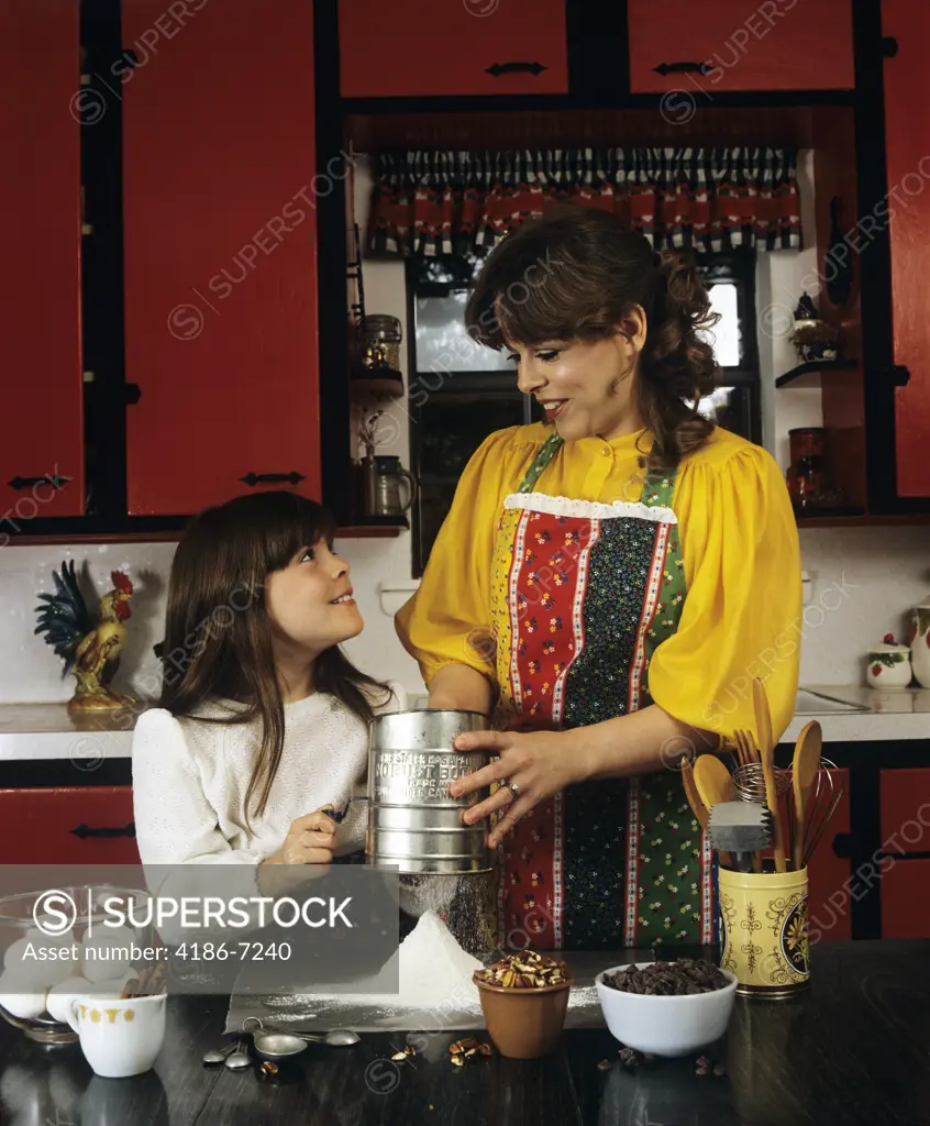 1980S Mother And Daughter Baking Sifting Flour In Kitchen