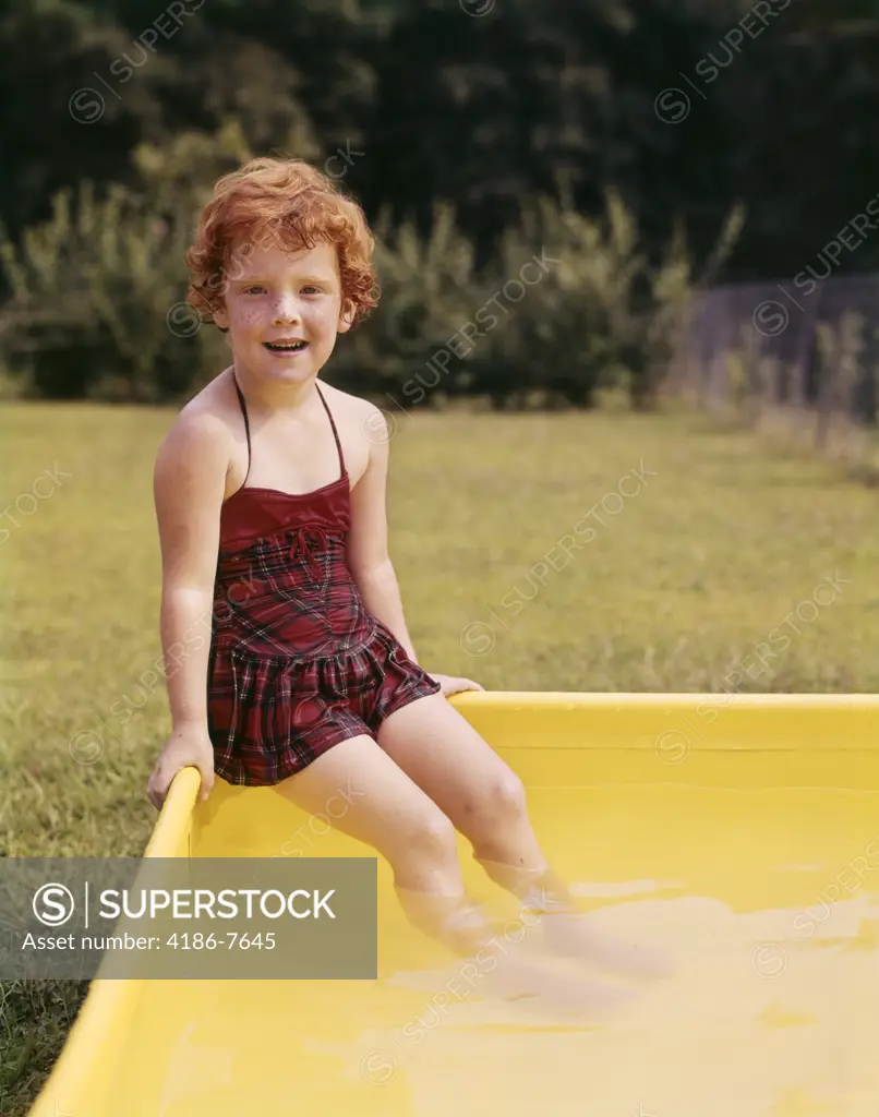 1960S Smiling Red Haired Little Girl In Plaid Bathing Suit Sitting On Yellow Plastic Backyard Swimming Pool