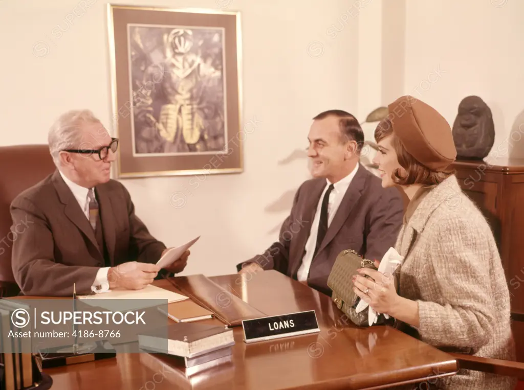 1960S Man Bank Loan Officer Interviewing Couple Man Woman At Desk In Mortgage Finance Office