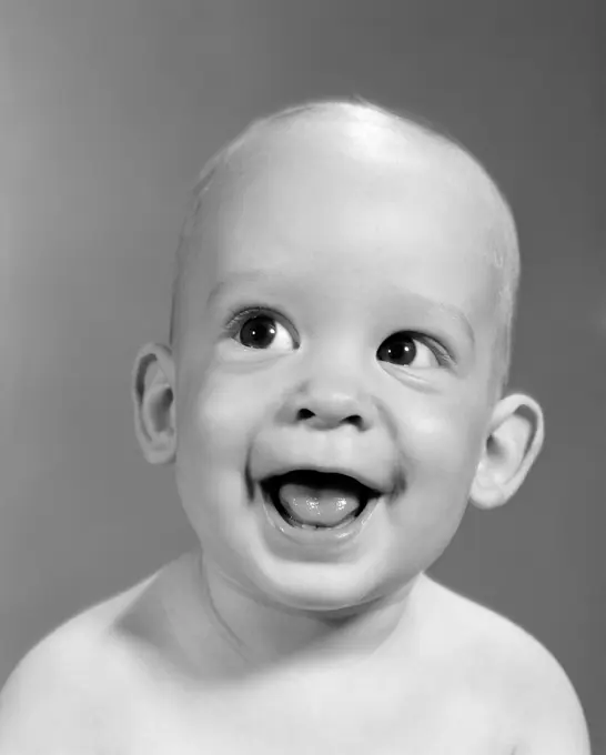 1960S Close-Up Portrait Of Nearly Bald Baby Smiling With Mouth Wide Open Looking Off To The Side